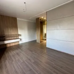 Quarto com piso de madeira e estrutura de cama em ambiente interno.