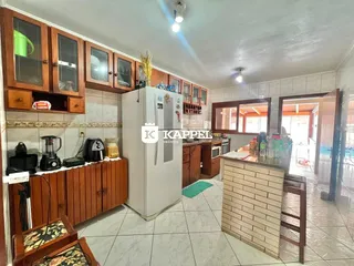 Foto interna de uma cozinha com armários de madeira e eletrodomésticos brancos.