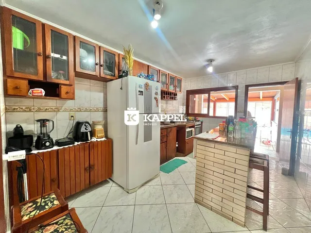 Foto interna de uma cozinha com armários de madeira e eletrodomésticos brancos.