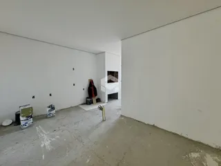 Espaço interno vazio com paredes brancas e piso de concreto em uma residência.