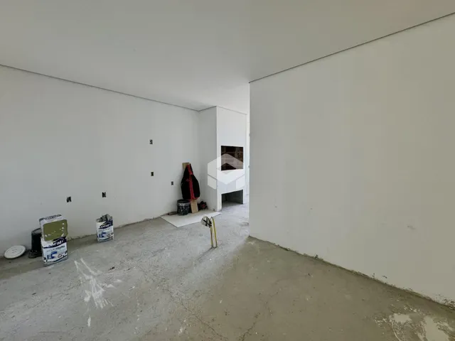 Espaço interno vazio com paredes brancas e piso de concreto em uma residência.