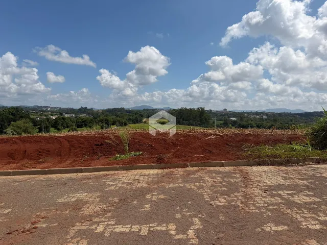 Paisagem de terra vermelha com vegetação ao fundo.