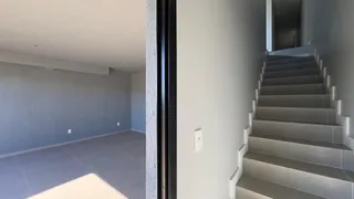 Vista interna de um ambiente com piso de cerâmica e escadaria em um imóvel.
