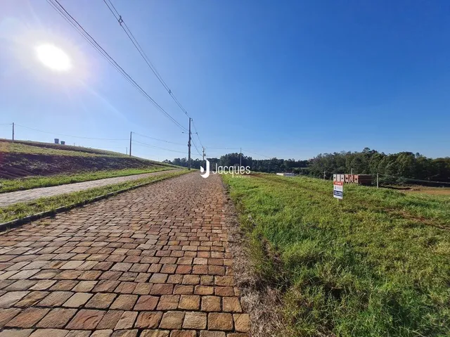 Um caminho de tijolos se estende por um campo gramado sob um céu azul.