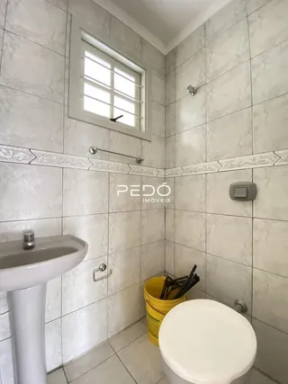 Um banheiro com paredes de azulejo claro e janela.