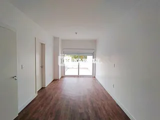 Hall de entrada com piso de madeira e porta de vidro que dá para o exterior.
