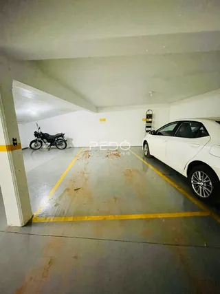 Foto de um espaço aberto com piso de concreto e veículo estacionado.