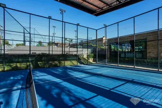 Imagem de uma quadra esportiva externa cercada por grade de segurança.