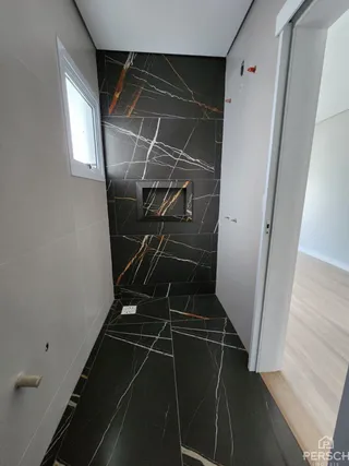 Foto de um corredor interno com revestimento de mármore preto e laranja.