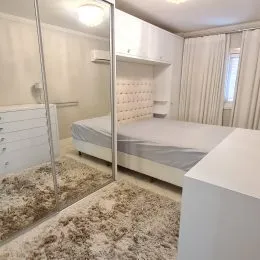 Quarto com cama e paredes brancas em um imóvel.