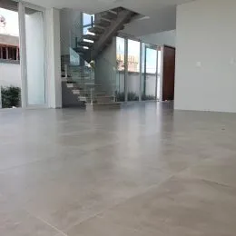 Vista interna de um ambiente amplo com piso de concreto polido e escadaria.