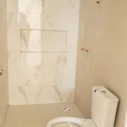 Banheiro com revestimento em mármore branco nas paredes.
