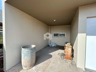 Espaço interno com paredes brancas e piso de concreto.