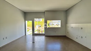 Ambiente interno de uma sala ampla com paredes cinzas e piso claro.