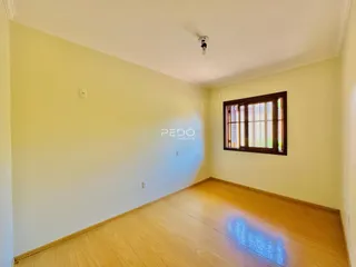 Vista interna de uma sala com piso de madeira clara e parede amarelada.