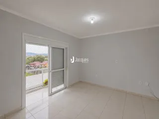 Ambiente interno com piso de cerâmica e porta de vidro abrindo para a área externa.