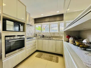Interior de uma cozinha moderna com armários claros e revestimento de azulejo.