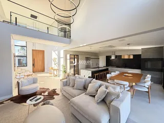 Sala de estar moderna com pé direito alto e varanda no andar superior.