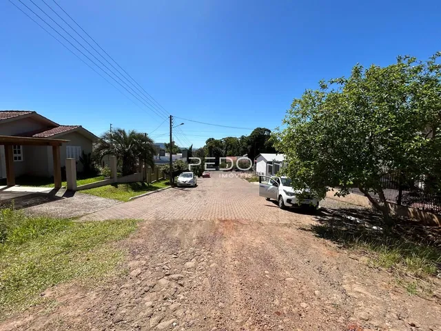 Vista externa de uma propriedade com terreno e vegetação ao redor.