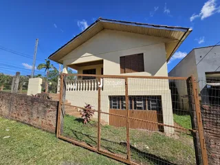 Fachada de uma casa em Lajeado, Brasil, com cerca de madeira e muro de tijolos.