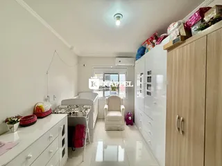 Quarto com cama e armário branco em ambiente claro.
