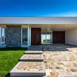 Fachada de uma residência com área externa pavimentada e gramado.