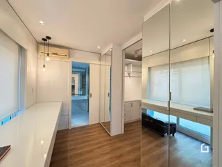 Sala de estar moderna com piso de madeira e espelhos.