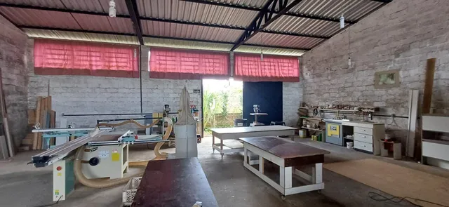 Interior de um espaço industrial com paredes de concreto e estrutura de telhado metálico.