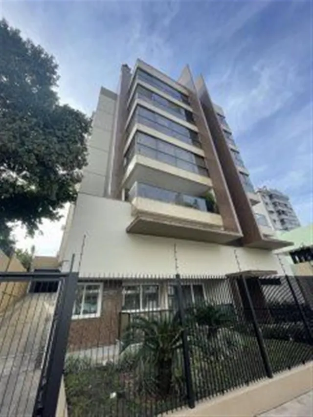 Fachada de um prédio residencial em Lajeado, Brasil, com cerca e vegetação no primeiro plano.