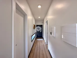 Corredor interno de uma residência com piso de madeira.