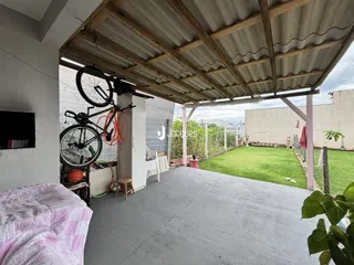 Área externa coberta com piso de concreto e jardim ao fundo.