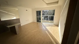 Sala de estar com piso de madeira clara e espelho na parede em um imóvel.