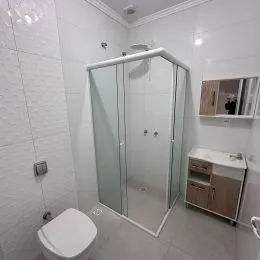Foto de um banheiro com box de vidro e revestimento branco.