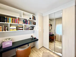 Ambiente interno de uma sala com estantes e portas de vidro espelhadas.