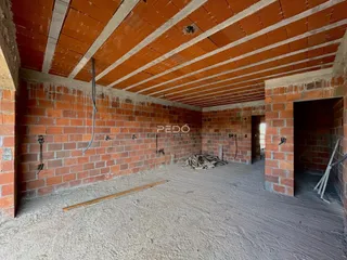 Interior de uma sala com paredes de tijolo aparente e teto de telhas.