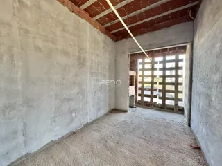 Interior de um cômodo com paredes brancas e teto de tijolos exposto.