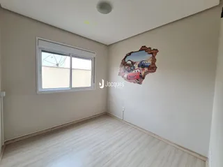 Uma sala interna com piso de madeira clara e paredes brancas.