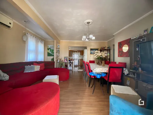 Sala de estar com decoração em tons de vermelho e piso de madeira.