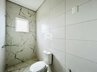 Foto de um banheiro com paredes revestidas de mármore e piso cerâmico.