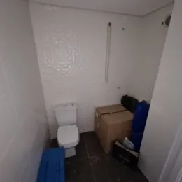 Foto de um banheiro interno com vaso sanitário e piso escuro.