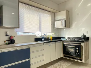 Cozinha moderna com armários brancos e bancadas escuras.