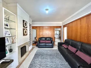 Sala de estar com sofá de couro e painéis de madeira.