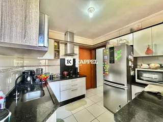 Foto interna de uma cozinha com armários brancos e bancadas escuras.