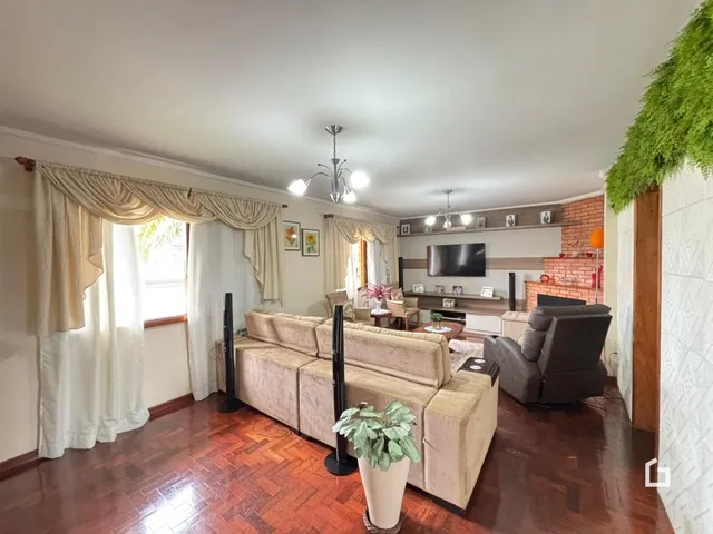 Sala de estar com piso de madeira e cortinas claras.