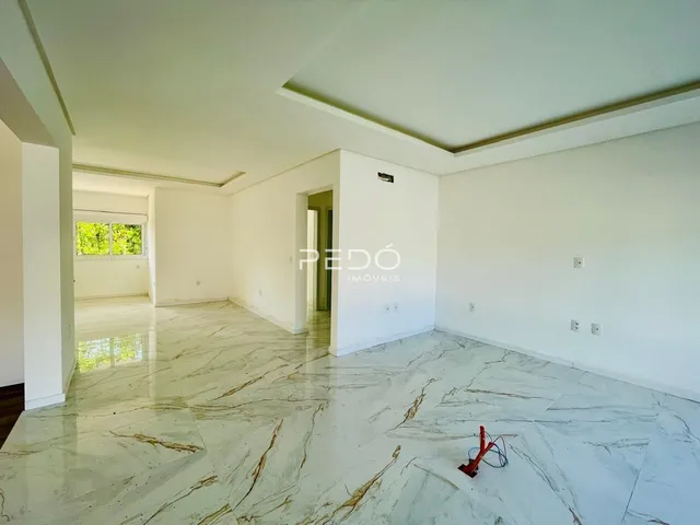 Ambiente interno amplo com piso de mármore claro e paredes brancas.