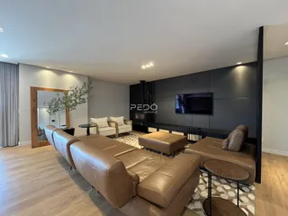 Sala de estar moderna com sofá de couro e piso de madeira clara.