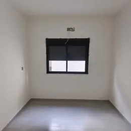 Foto de um cômodo interno com paredes brancas e uma janela escura.