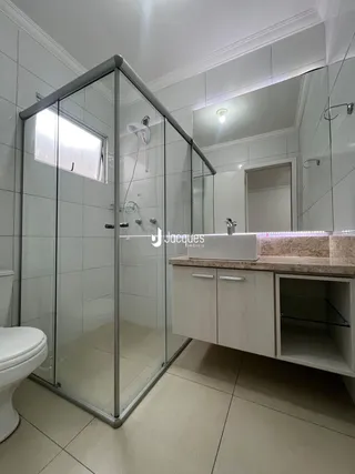 Banheiro com box de vidro e bancada de madeira.