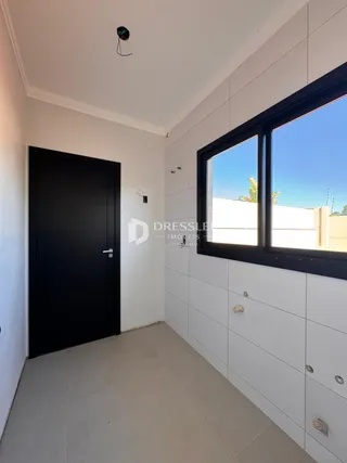 Vista interna de um corredor com paredes brancas e porta escura.