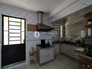 Vista interna de uma cozinha com revestimento de azulejos brancos e armário claro.